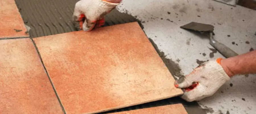 A man with gloves and equipment is gluing tiles with tile adhesive