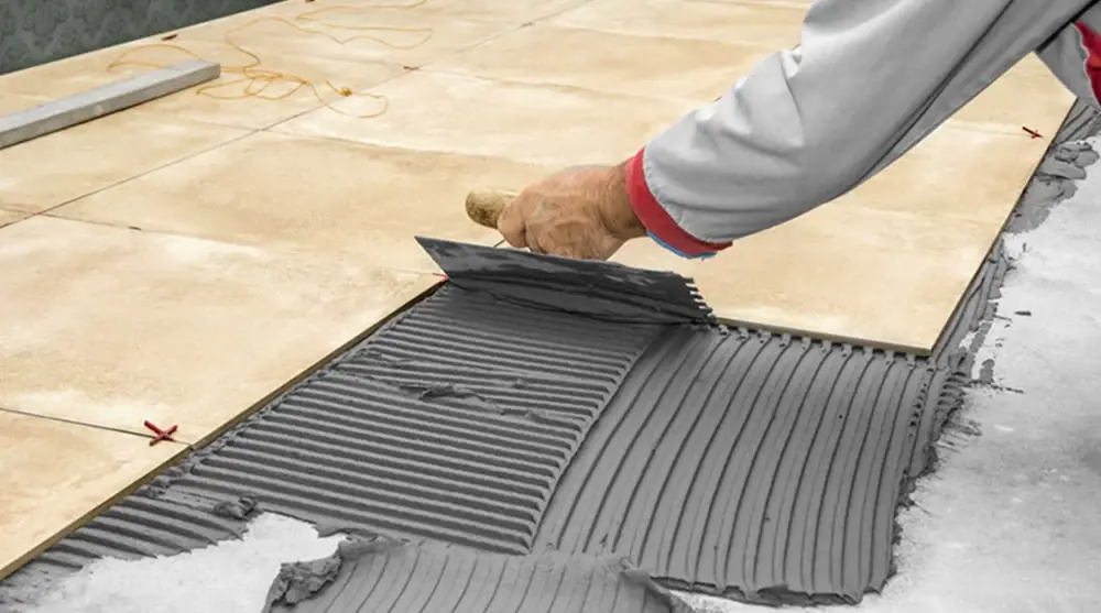 A man with a trowel is gluing tiles with tile adhesive