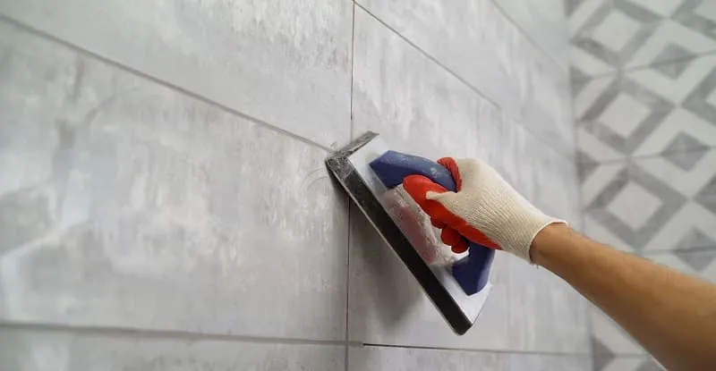 A man is installing wall tiles