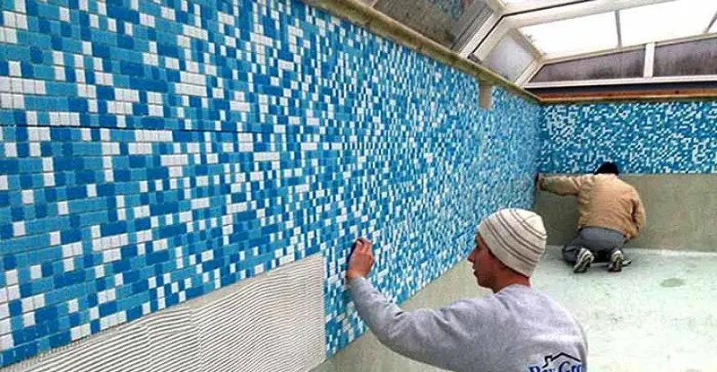 Two men are tiling the wall
